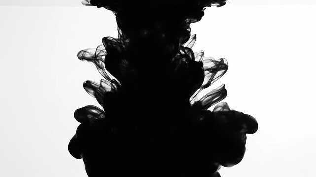 Black ink swirling in water with abstract smoke shapes on white background