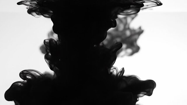 Black ink swirling in water with abstract fluid shapes and smoky patterns on white background