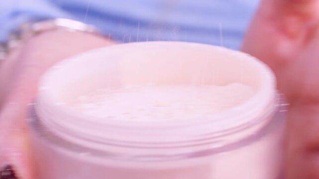 Loose powder. Cosmetic dusting. Unrecognizable woman professional cosmetologist hands holding makeup product.