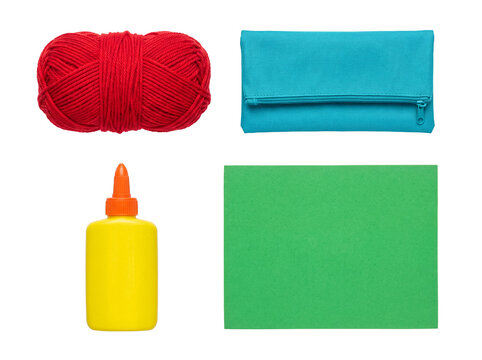 An essential collection of colorful craft supplies including red yarn, a turquoise case, glue, and green foam.