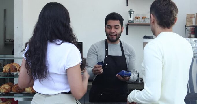 young latin man barista preparing and selling coffee and customer paying with credit card in a coffeeshop in Mexico Latin America