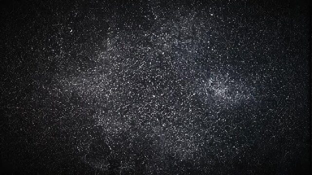 Close up of fine white powder particles suspended in the air on a dark background with soft lighting effects