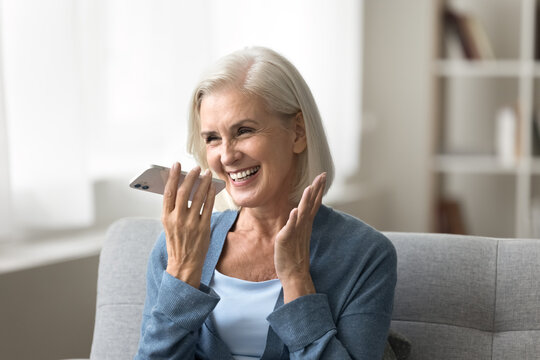 Voice app. Cheerful excited elderly woman grandmother hold smartphone by mouth dictate request to virtual assistant record vocal message. Happy aged lady use phone loudspeaker for easy communication
