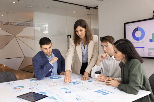 Female business leader presenting company analytics to diverse consulting team explaining statistic results interpreting marketing campaign reports on strategic planning meeting in conference room