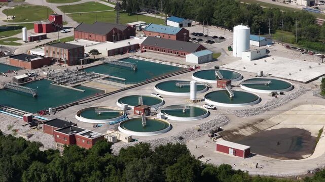 Aerial of wastewater treatment plant facility in Fairmont City Illinois with numerous circular clarifier tanks and industrial buildings