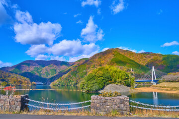 Fototapeta premium 紅葉の神奈川県山北町の三保ダムの天端道路(遊歩道)から北西側の眺望(永歳橋,ミツバ岳,世附大橋など)