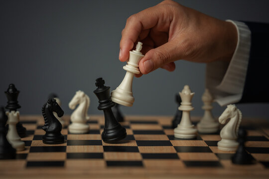business hand holding white chess king taking black king, checkmate concept