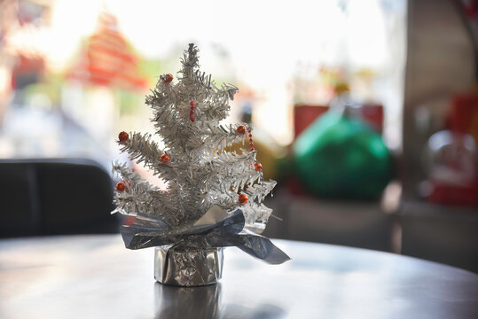 Close-up view of Christmas gifts under a decorated tree with red wrapping in a cozy home interior.