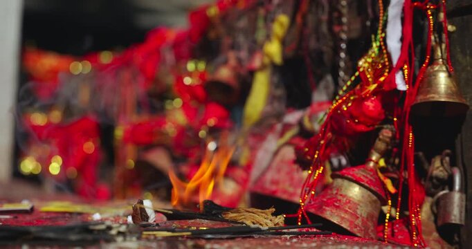 Mustang, Annapurna Circuit, Muktinath, Nepal, static shot of burning incense sticks, ritual fire, and ceremonial brass bells and red clothes