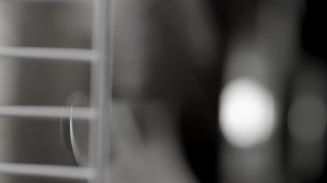 Metal fan blades turn behind a grille in a soft indoor close up with blurred
