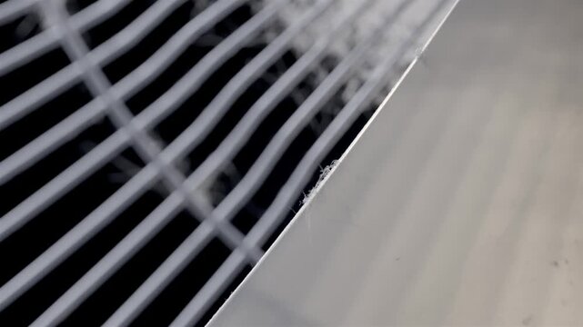 White oscillating fan grille gathers dust and lint against a black background.