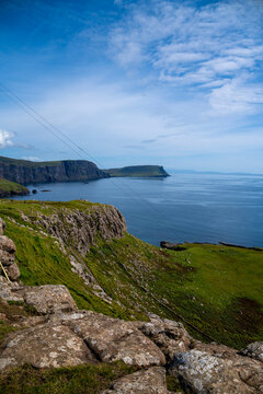 Coastal cliffs and winding path overlooking the sea on Isle of Skye under blue sky