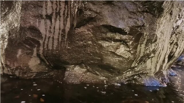Water dripping down a dark cave rock wall