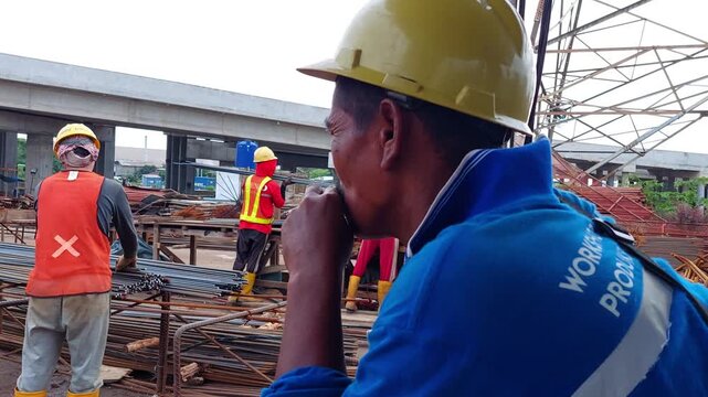 An old man smokes a cigarette while watching the construction workers.