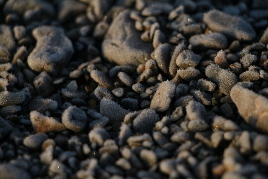Frost-covered pebbles on the shore of Lake Sevan, Armenia, illuminated by warm sunlight