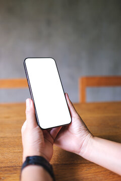 Vertical mockup image of a woman holding mobile phone with blank desktop screen