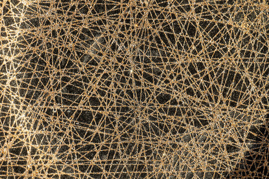 Abstract macro detail of golden tangled fiber texture on a dark background, creating an intricate web pattern suitable for backgrounds, design, luxury, craft and material concepts.