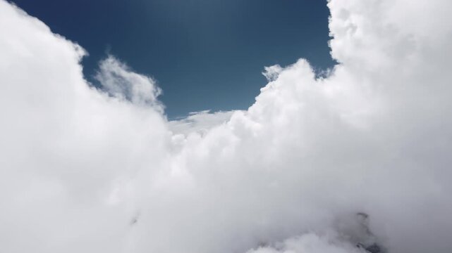 Camera moving forward through cumulus clouds in blue sky