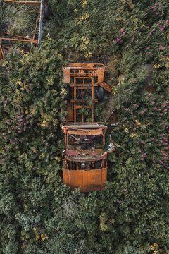 Aerial view of a rusted abandoned truck frame surrounded by tall grass and wildflowers in Unalaska, Alaska, United States.
