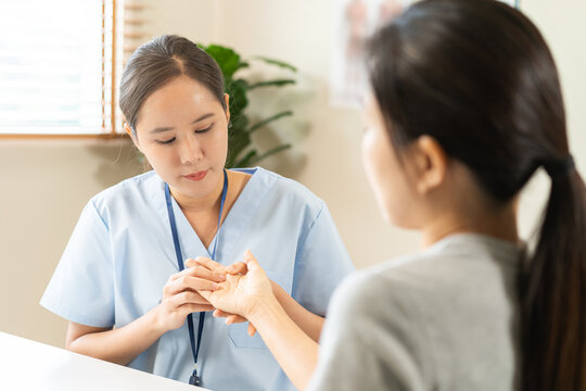 Asian young woman physical therapist examining and massaging a patient trigger fingers and wrist for hand joint rehabilitation, arthritis diagnosis and office syndrome occupational therapy concept.