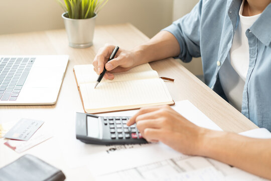 Saving money wealth concept, asian young business man, male using calculator for calculate saving cost, cash finance planning to spend enough money on his income for save money, payment tax, investing