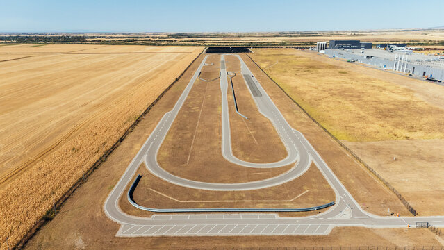 Aerial view of a vehicle test track surrounded by agricultural fields and industrial facilities in Indjija, Vojvodina, Serbia.
