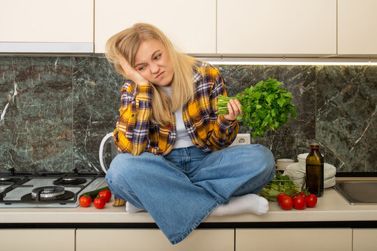 Woman sits on kitchen counter looking frustrated while preparing meal