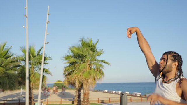 Athletic man with braids shooting basketball on beach court