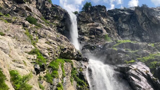 Hiker pausing in front view beside Shdugra waterfall near Mazeri, Svaneti, Georgia, travel scene for trekking achievement, guided tours, destination branding, and outdoor adventure promotion.
