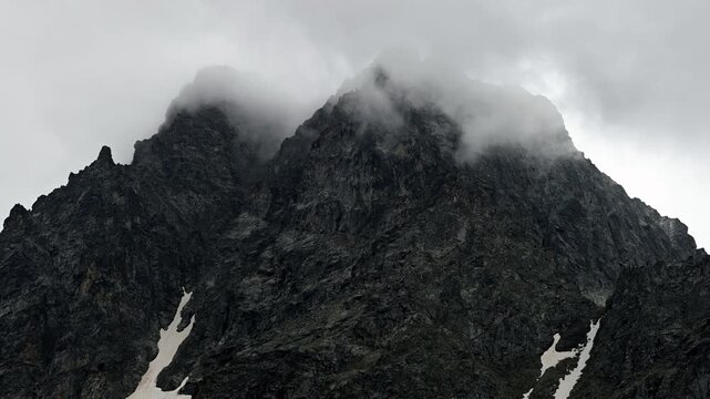 Clouds drifting across dark rocky mountain peaks