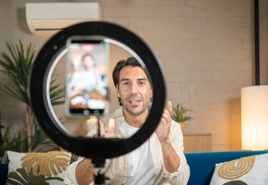 Man recording a video for social media using a smartphone and ring light