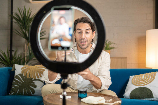 Man recording video for social media about skincare products at home