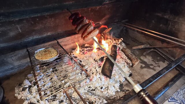 Dry firewood burns with bright flames inside a barbecue pit to prepare hot embers for Argentine asado.