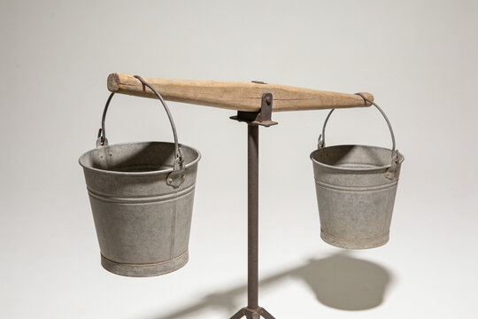 Wooden yoke tilted with one full bucket and one nearly empty