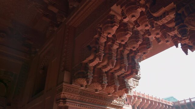 Static low angle close up shot of intricately carved red sandstone ornamental brackets at Jahangiri Mahal inside Agra Fort in Uttar Pradesh, India.