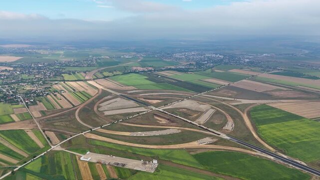 Aerial drone footage showing the large-scale road interchange near Pașcani, Romania, planned to connect the A7 and A8 motorway corridors, surrounded by agricultural fields