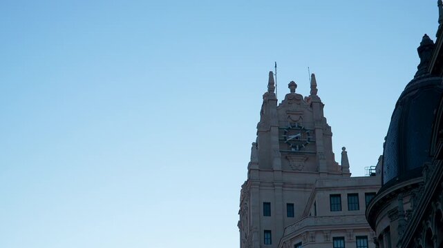 A low angle shot of the iconic Telefonica building clock tower in Madrid against a clear blue sky. Suitable for travel documentaries and urban architecture features.