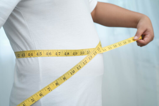 Asian woman with fat belly big size overweight and obesity with measure tape.