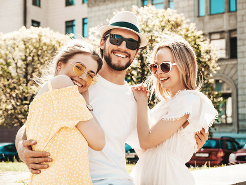 Group of young three stylish friends posing in the street. Fashion man and two cute female dressed in casual summer clothes. Smiling models having fun in sunglasses.Cheerful women and guy going crazy
