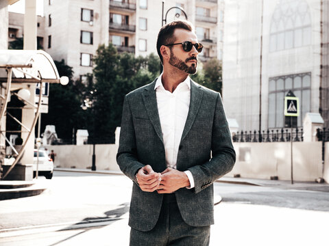 Portrait of handsome confident stylish hipster lambersexual model.Sexy modern man dressed in elegant suit. Fashion male posing in the street background in Europe city at sunset. In sunglasses