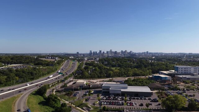 Aerial of Nashville Tennessee downtown skyline and highway interchange with multilane interstate and commercial buildings with large parking lots
