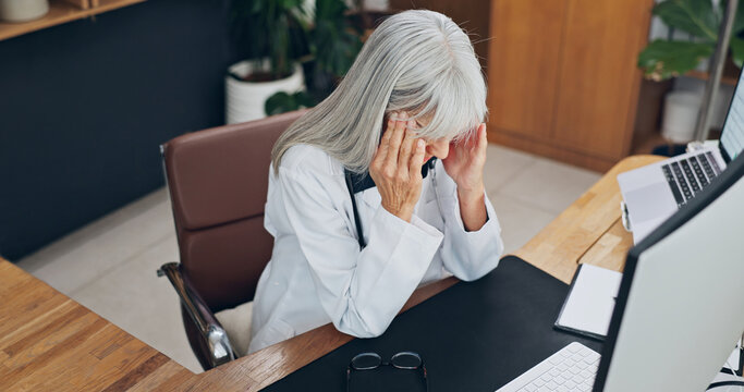Stress, headache and doctor in office at clinic with fatigue, burnout or bad news on patient results. Woman, migraine and mature healthcare worker with exhaustion for medical mistake in hospital.