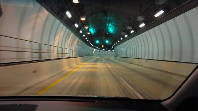 Driving through a brightly lit tunnel at night with green arrows indicating the path ahead, following a large semi-truck.