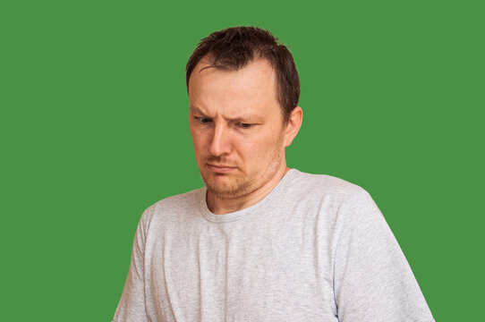 Man with a disgusted expression looking down with furrowed brows