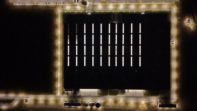 Aerial view of the North Industry industrial facility at night, featuring a large rectangular building with illuminated skylights and perimeter lighting in Pancevo, Serbia.