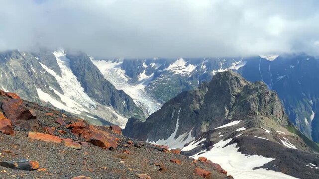 Glacier descending wide view between rugged peaks in Svaneti, Georgia, showing high-altitude terrain, summer snowfields, glacial landforms, and mountain geography for tourism, environmental content