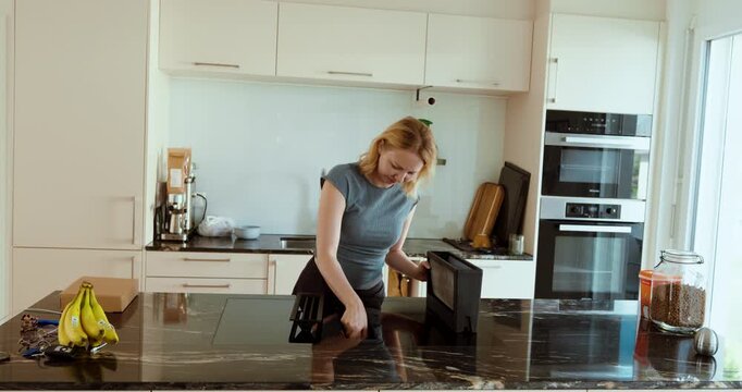 Woman removing and cleaning a kitchen extractor filter, representing appliance maintenance, grease removal, household cleaning, and kitchen hygiene.
