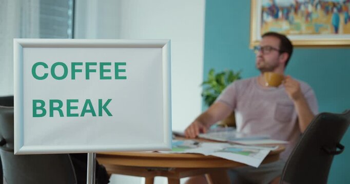 Man enjoying a cup of coffee during a work break, representing relaxation, workplace routine, rest, refreshment, and taking a pause from work.