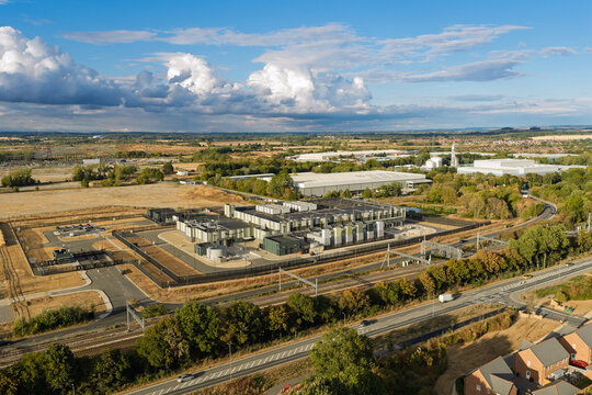 Aerial view of a data center complex surrounded by roads, trees, and fields in the United Kingdom.