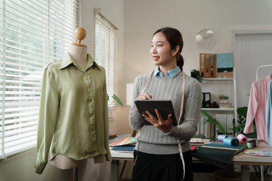Creative fashion designer atelier sketching on digital tablet in studio